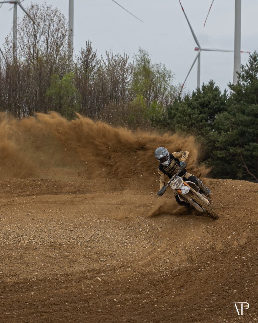 Motocross-Fahrer in der Sandkurve mit aufgewirbeltem Staub