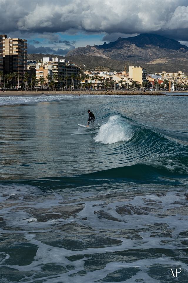 Surfer vor Küstenstadt und Bergen